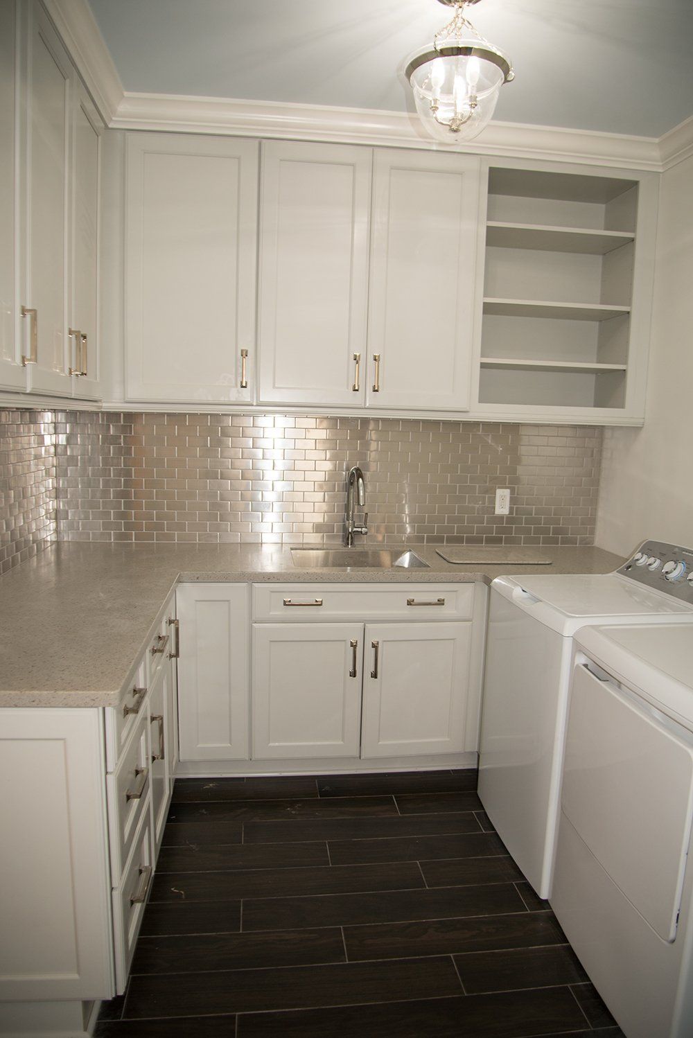 A laundry room with white cabinets , a washer and dryer , and a sink.