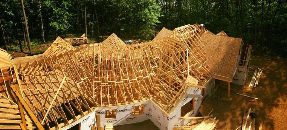 A large wooden house is being built in the middle of a forest.