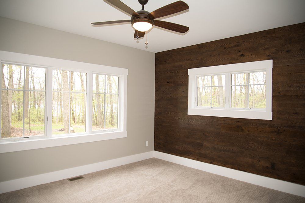 An empty room with a wooden wall and a ceiling fan.