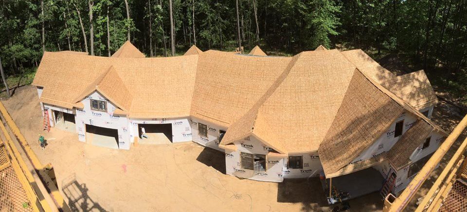 An aerial view of a large house under construction with a wooden roof.