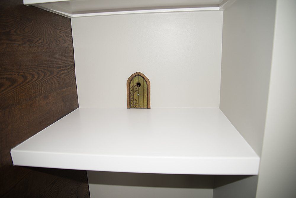 A white shelf with a small door on it