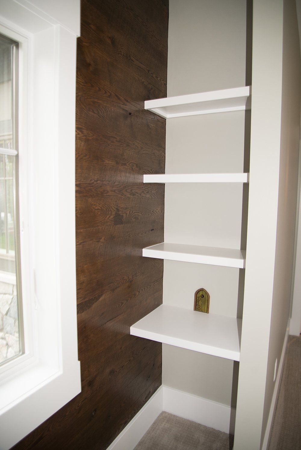 A corner of a room with shelves and a window