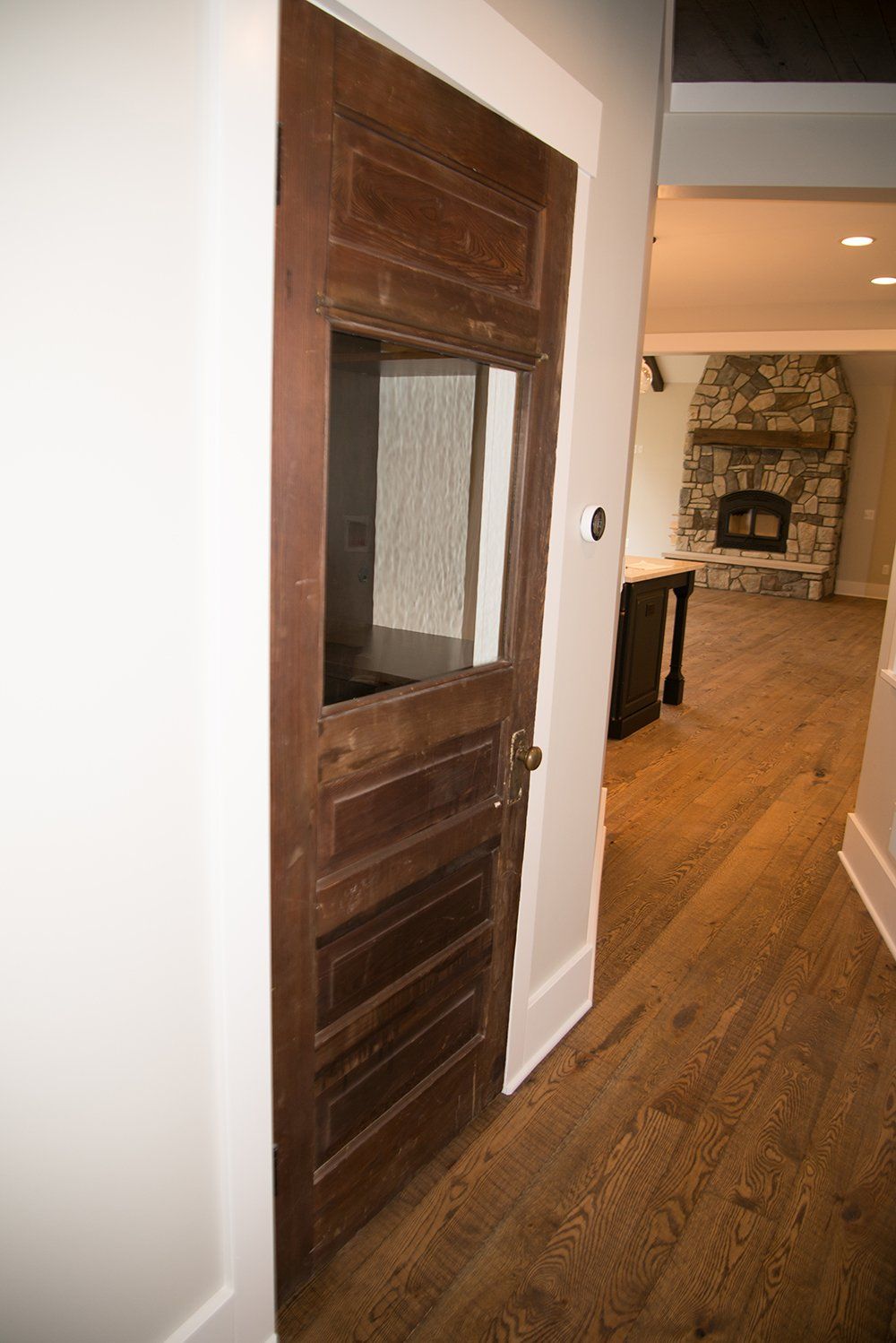 A wooden door with a glass window in a hallway leading to a living room.