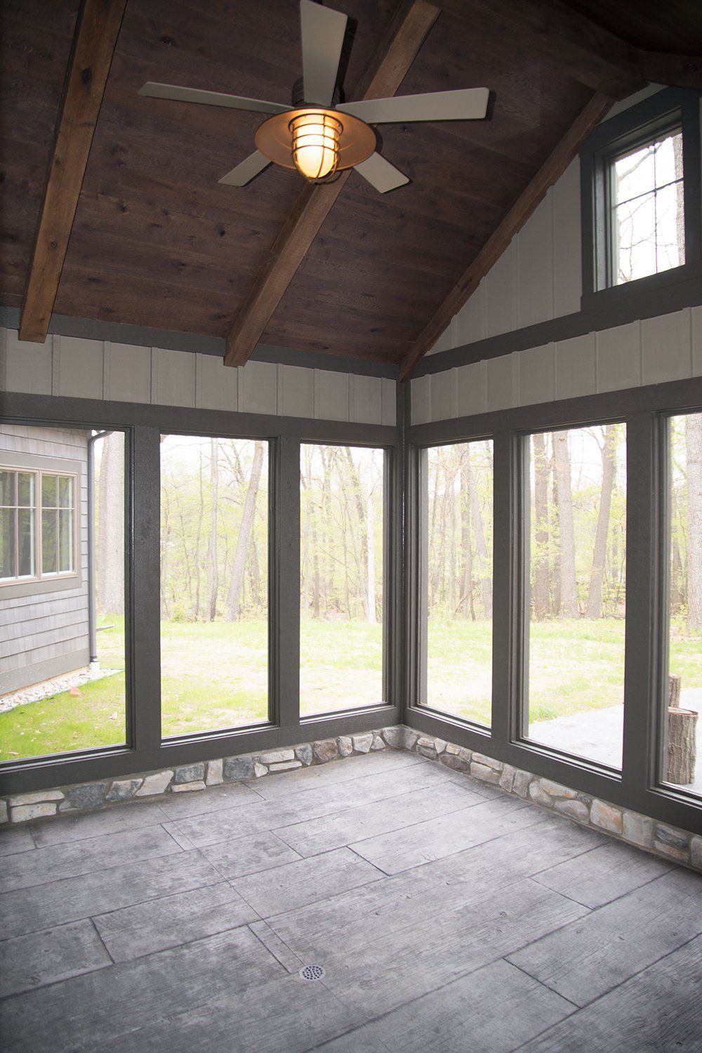 A screened in porch with a ceiling fan and lots of windows.