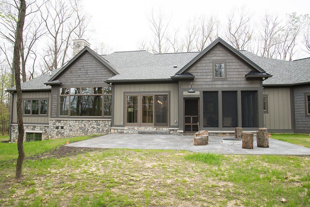 The back of a large house with a screened in porch.