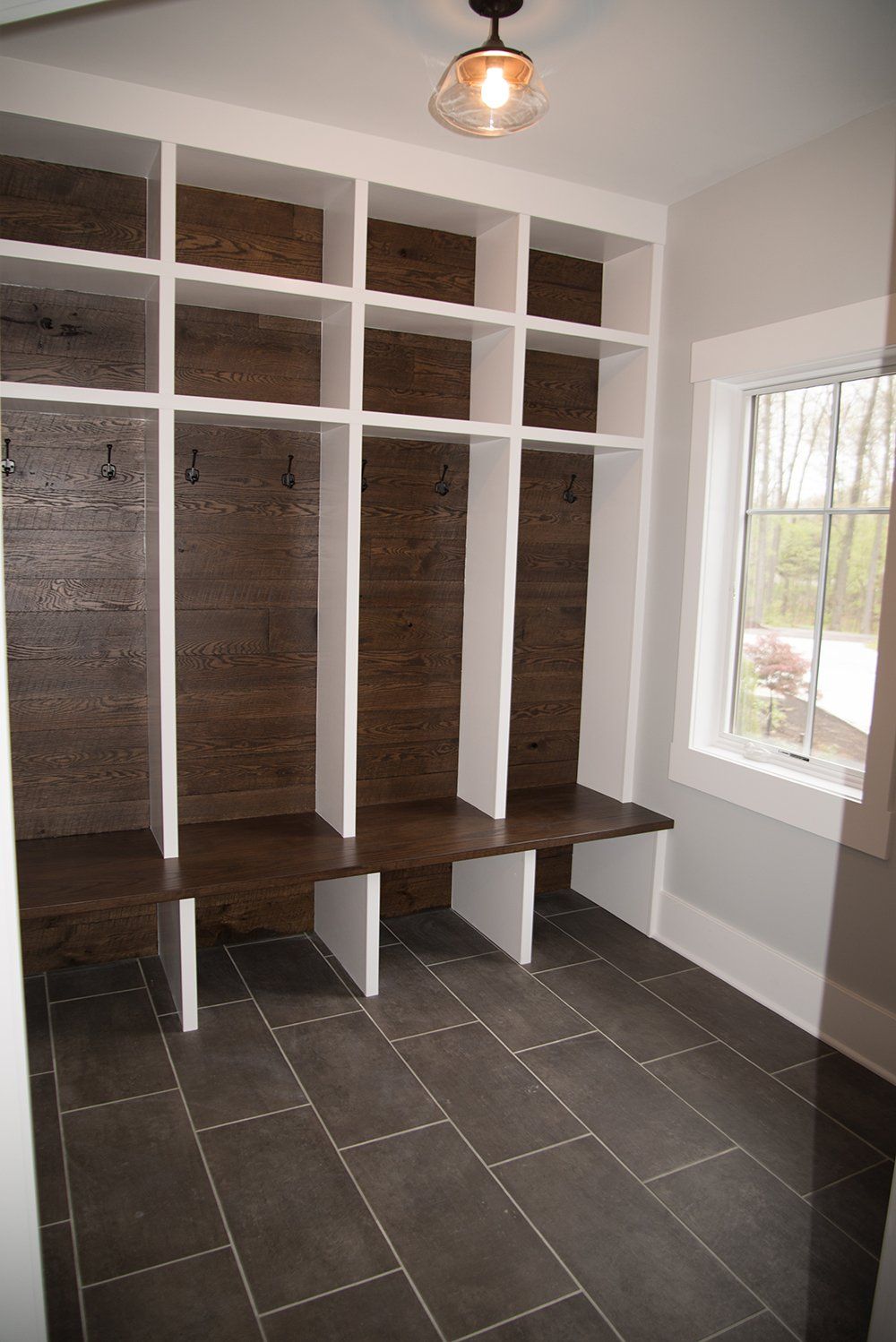 A mud room with wooden shelves and benches and a window.