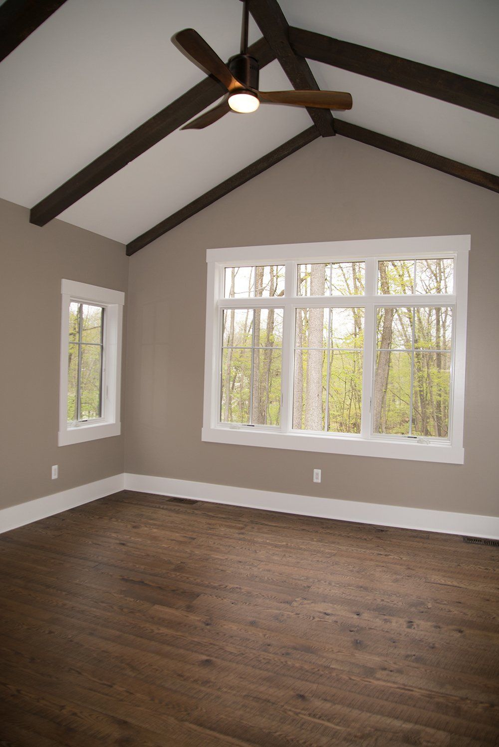 An empty room with a vaulted ceiling and a ceiling fan.