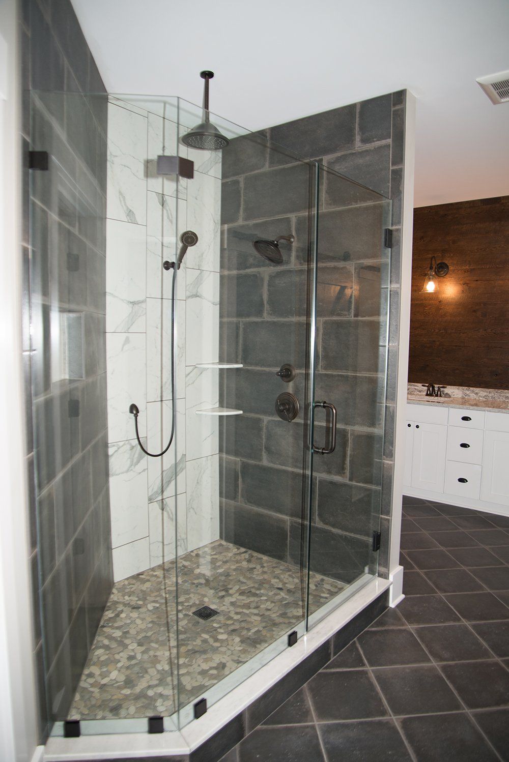 A bathroom with a walk in shower with a glass door.