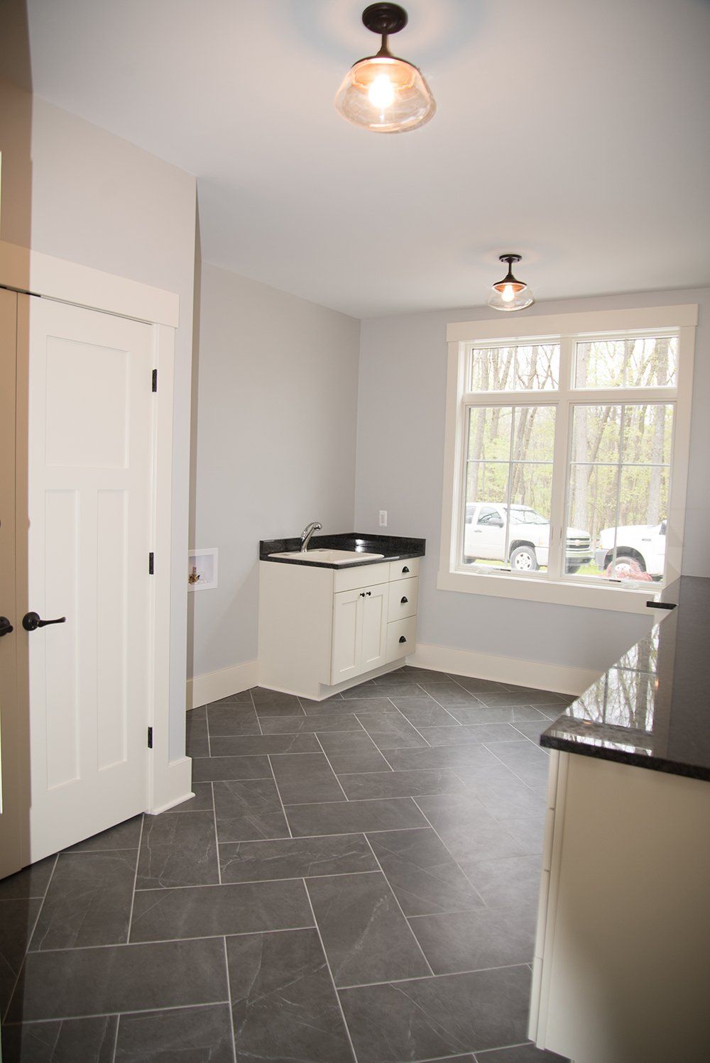 A laundry room with a sink , cabinets , and a window.