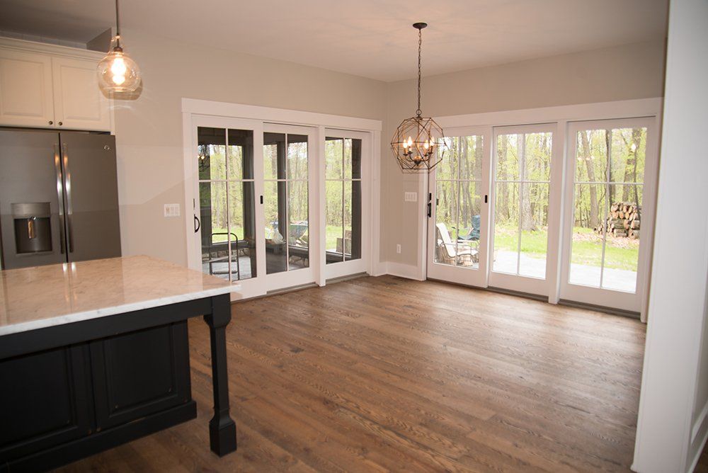 An empty kitchen with hardwood floors and sliding glass doors.