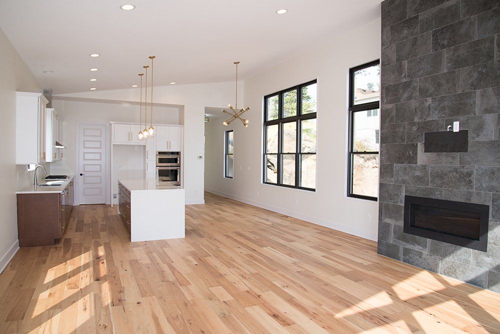 A living room with hardwood floors , a fireplace , and a kitchen.