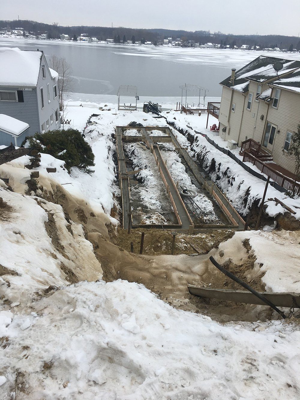 There is a lot of snow on the ground and a house in the background.