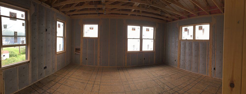 An empty room with a lot of windows in a house under construction.