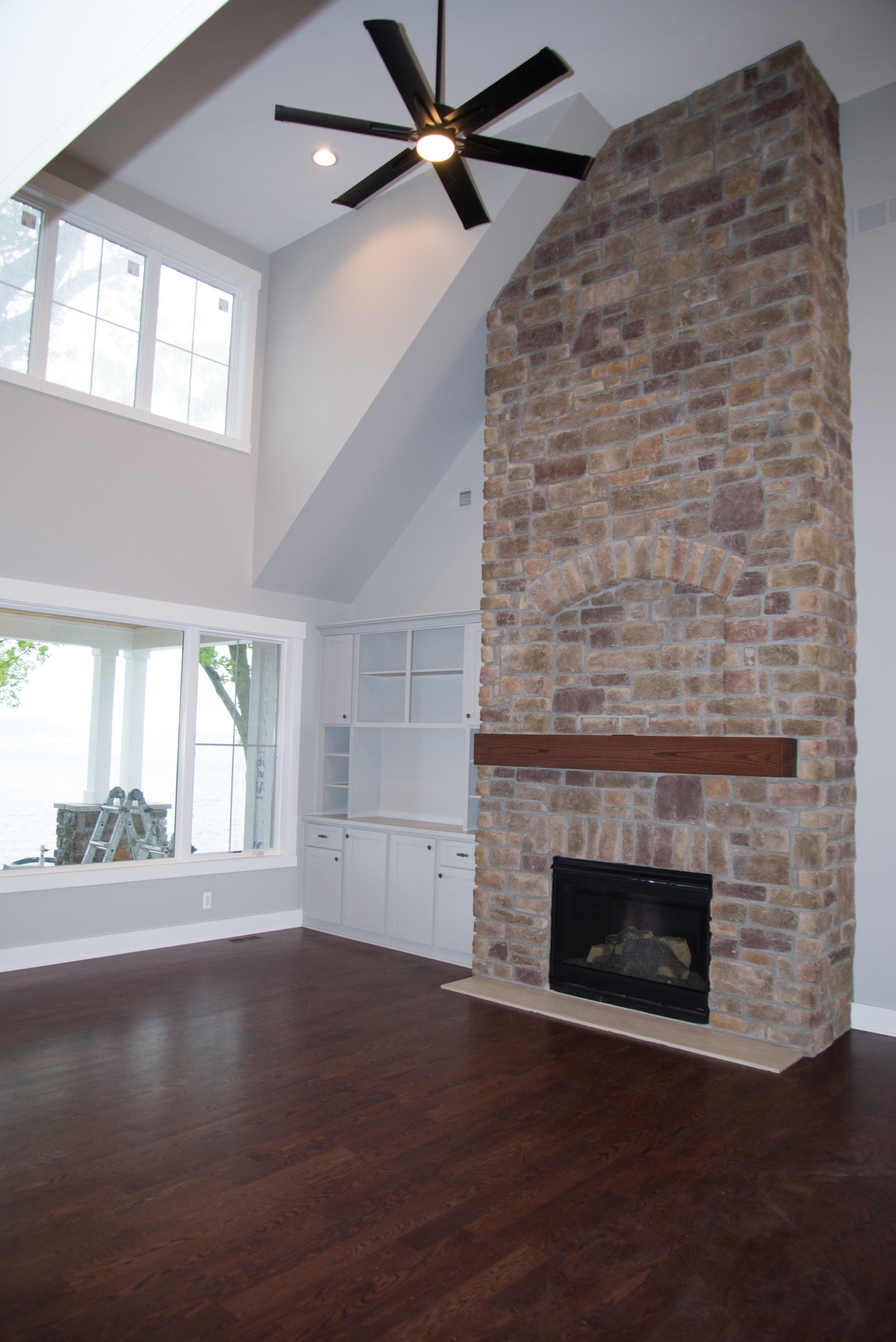 A living room with a fireplace and a ceiling fan