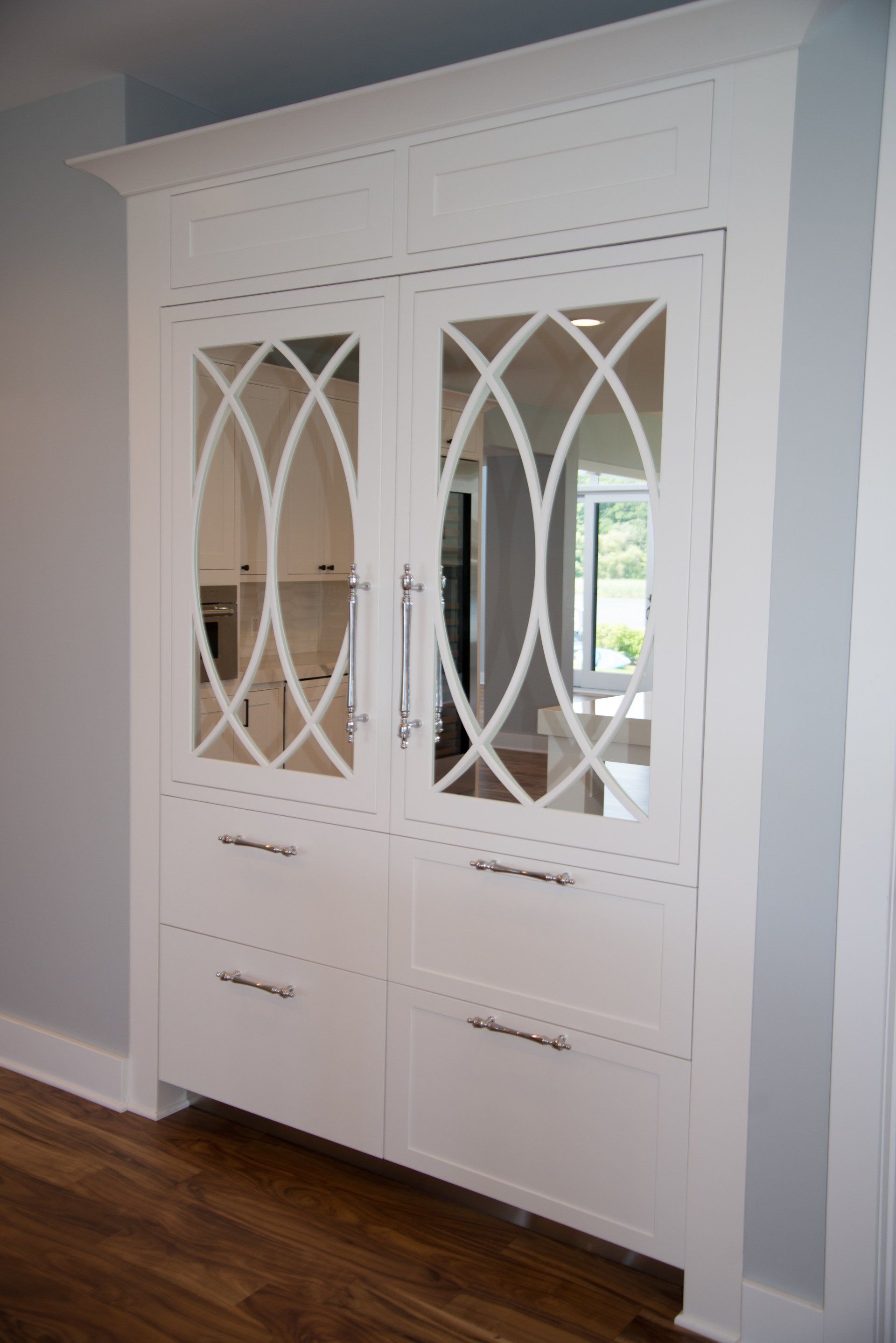 A white cabinet with mirrored doors and drawers in a kitchen.