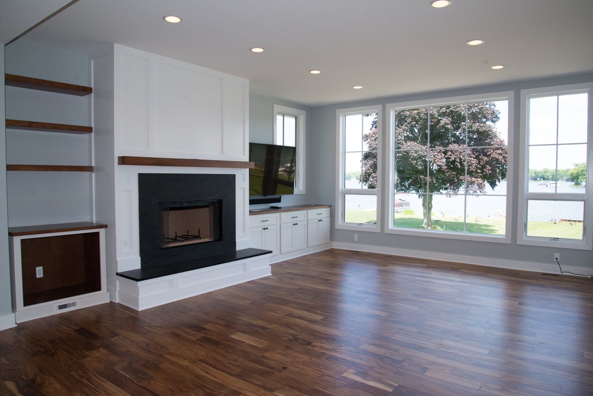 An empty living room with a fireplace and lots of windows