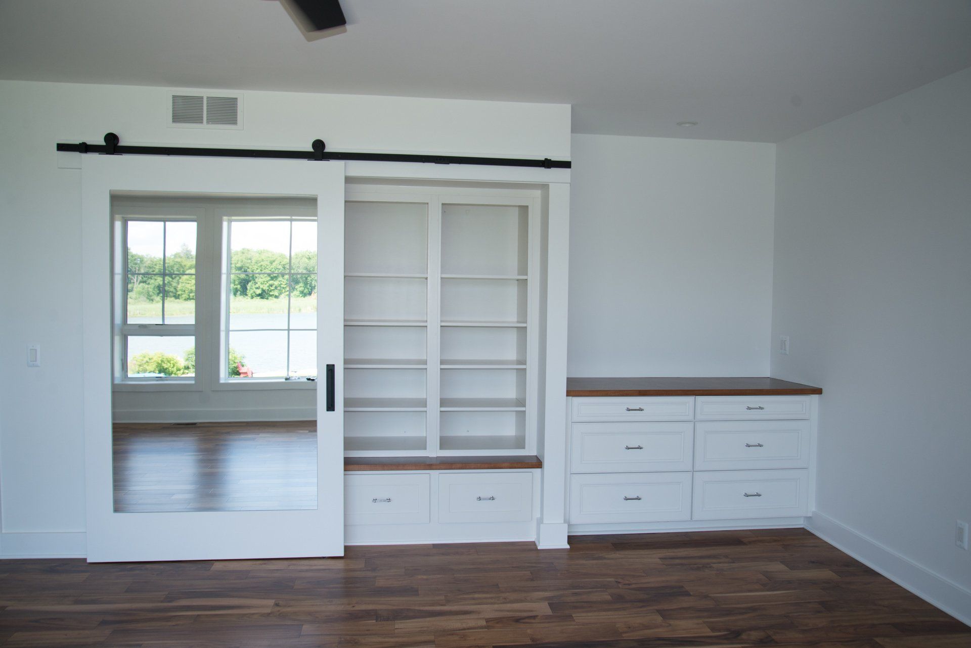 An empty room with a sliding barn door and shelves