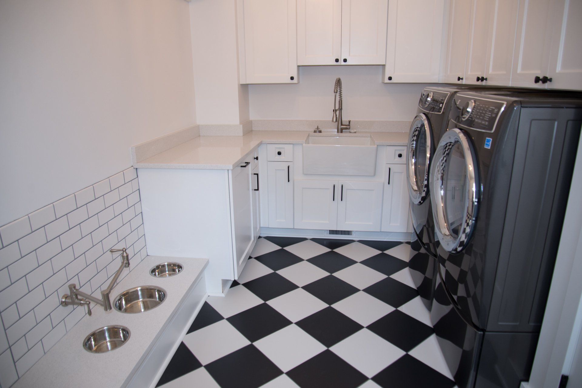 A laundry room with a black and white checkered floor and a sink.