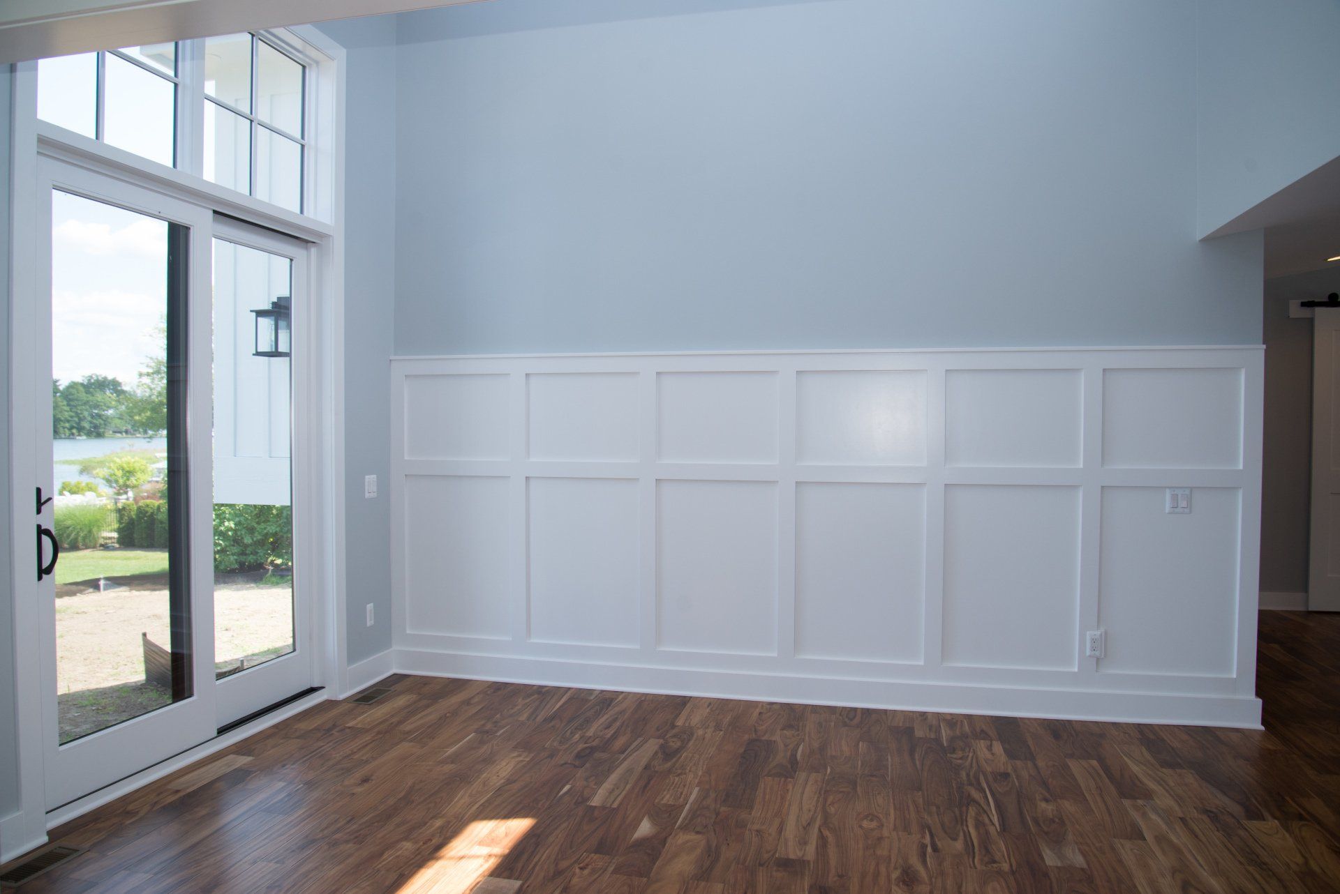 An empty living room with hardwood floors and a large window.