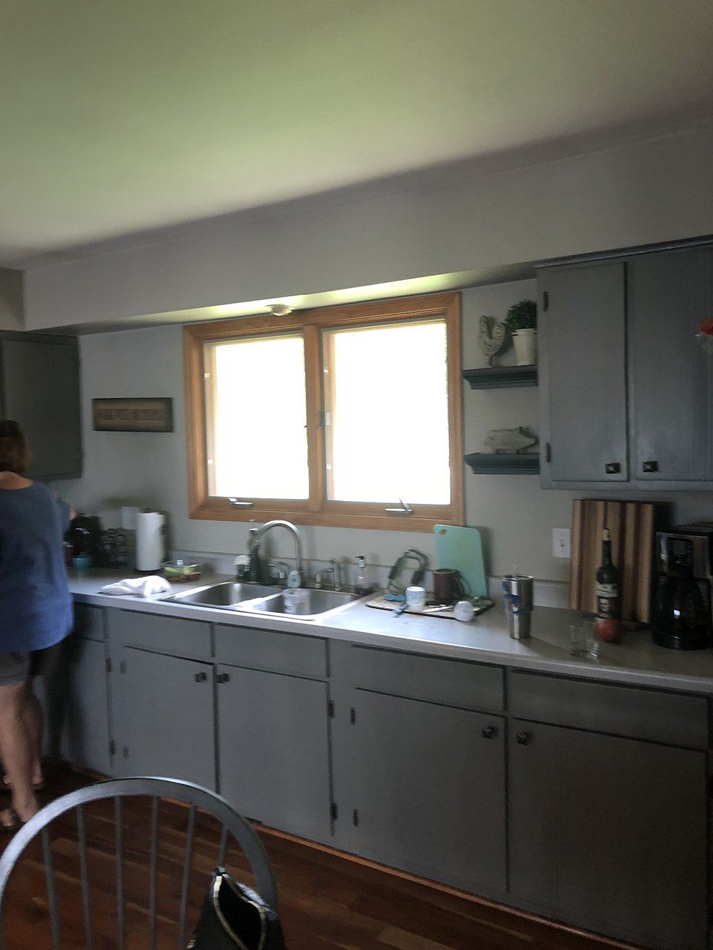 A kitchen with gray cabinets and a large window