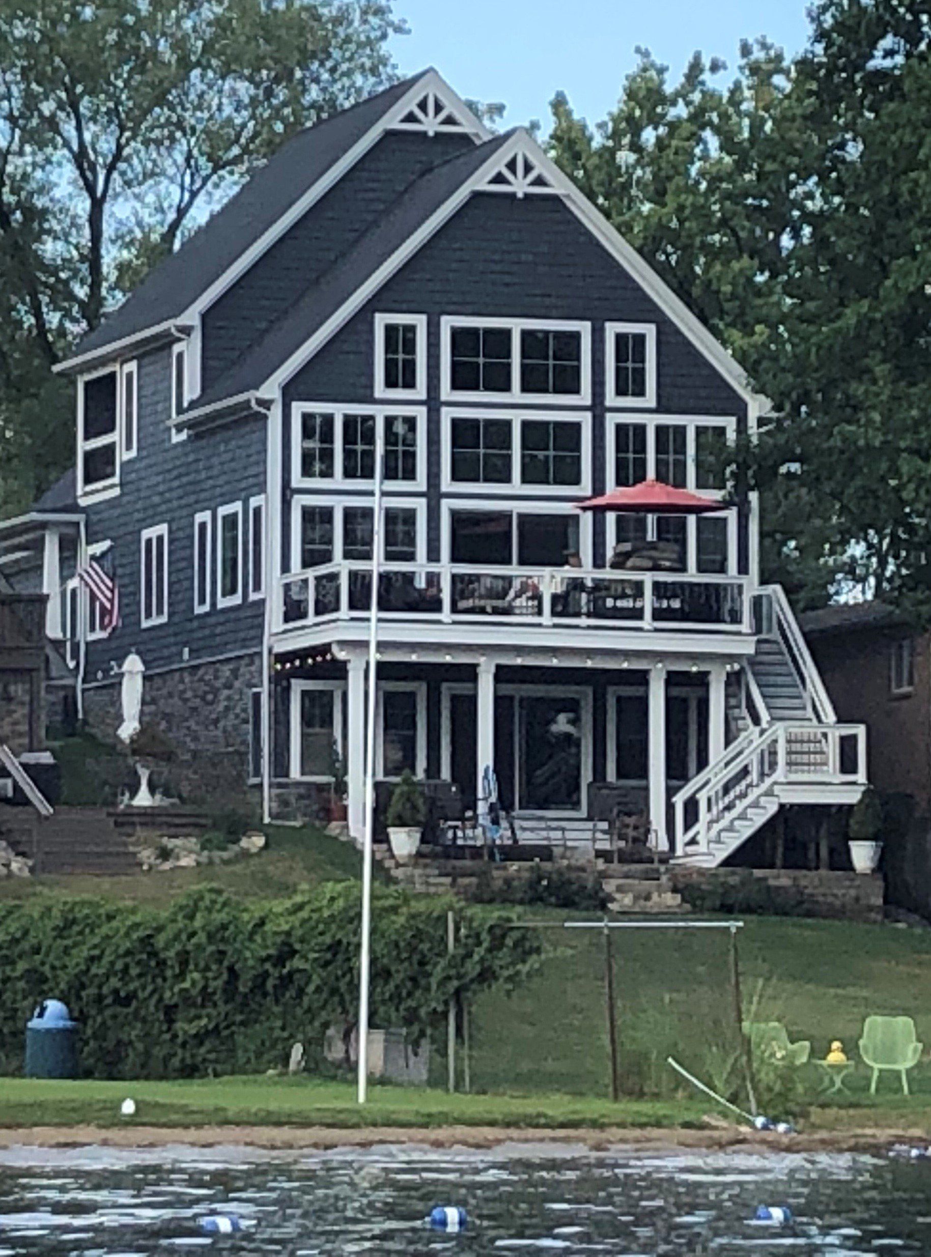 A large house with a lot of windows sits next to a body of water.