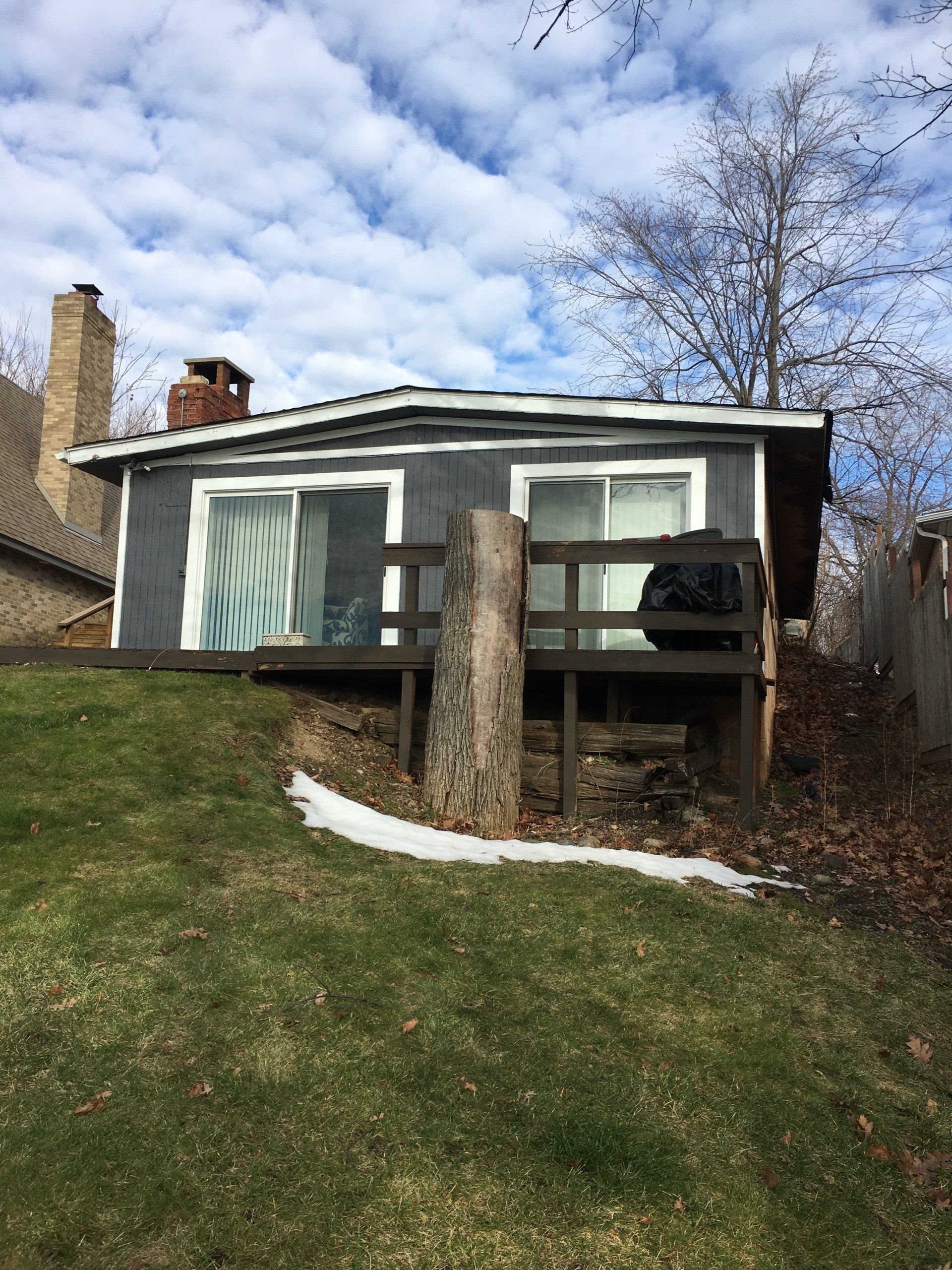 A small house with a deck and a chimney in the backyard.