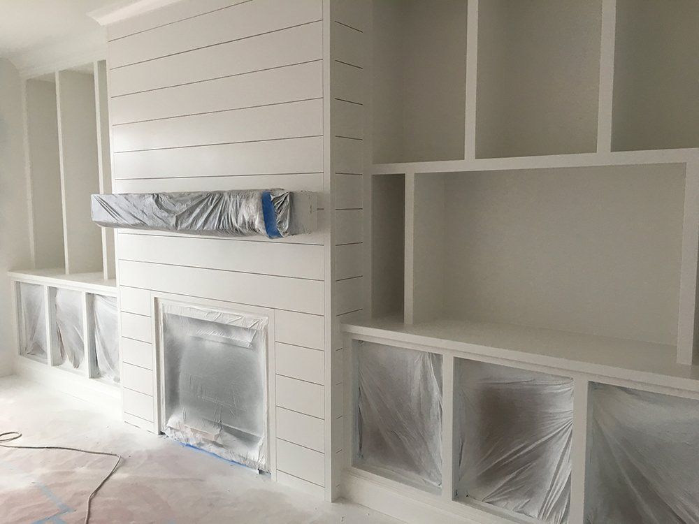 A living room with a fireplace and shelves covered in plastic.