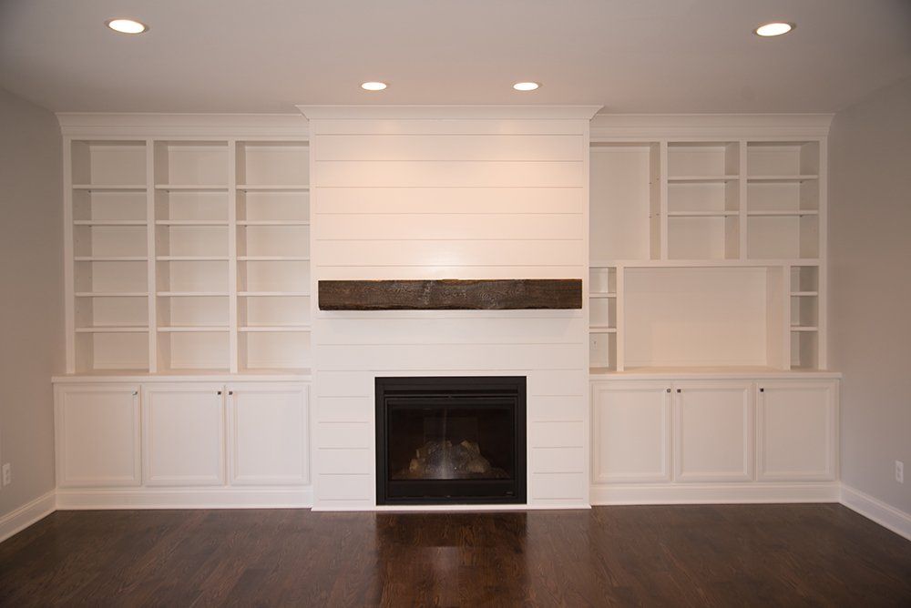 An empty living room with a fireplace and shelves.