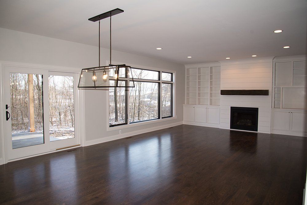 An empty living room with a fireplace and lots of windows
