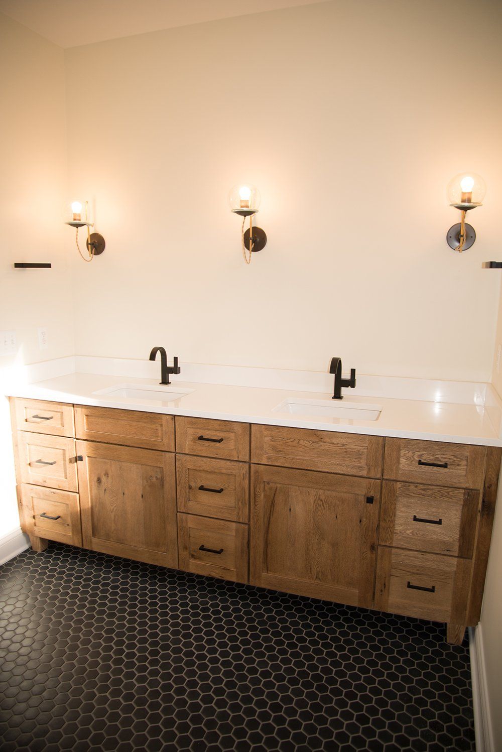 A bathroom with two sinks and a black tile floor.
