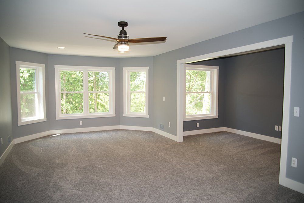An empty room with a ceiling fan and a lot of windows