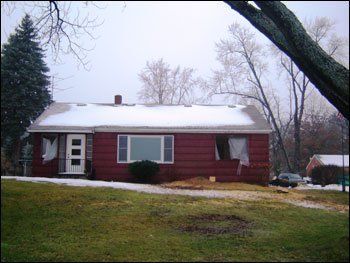 A small red house with snow on the roof