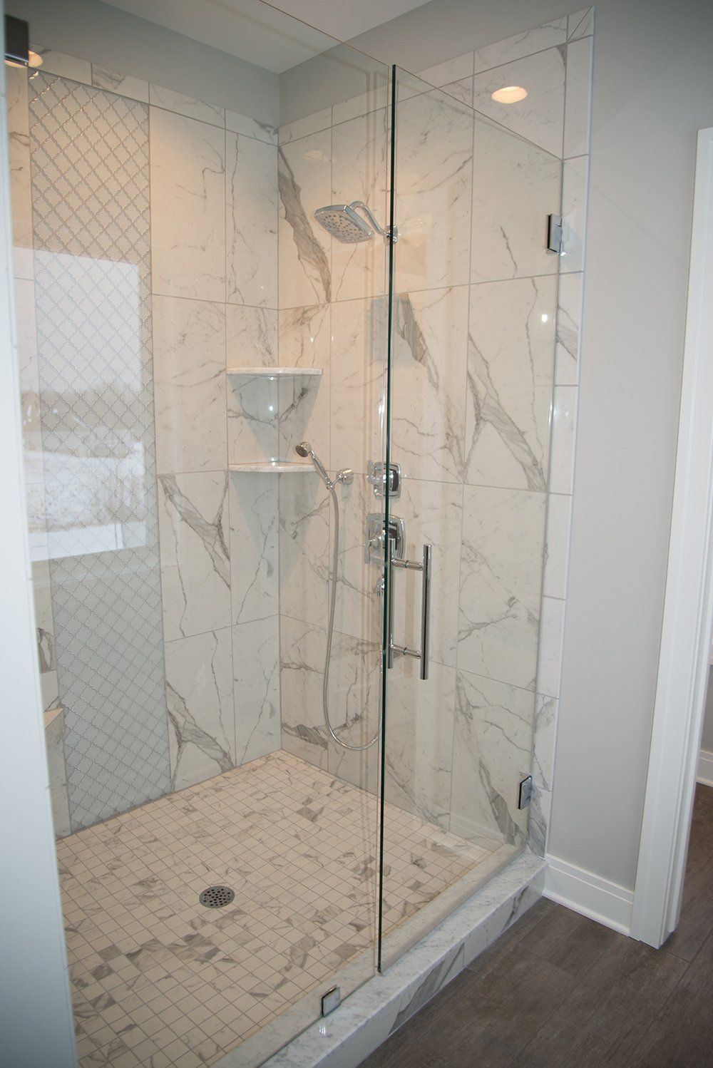 A bathroom with a walk in shower with a glass door.