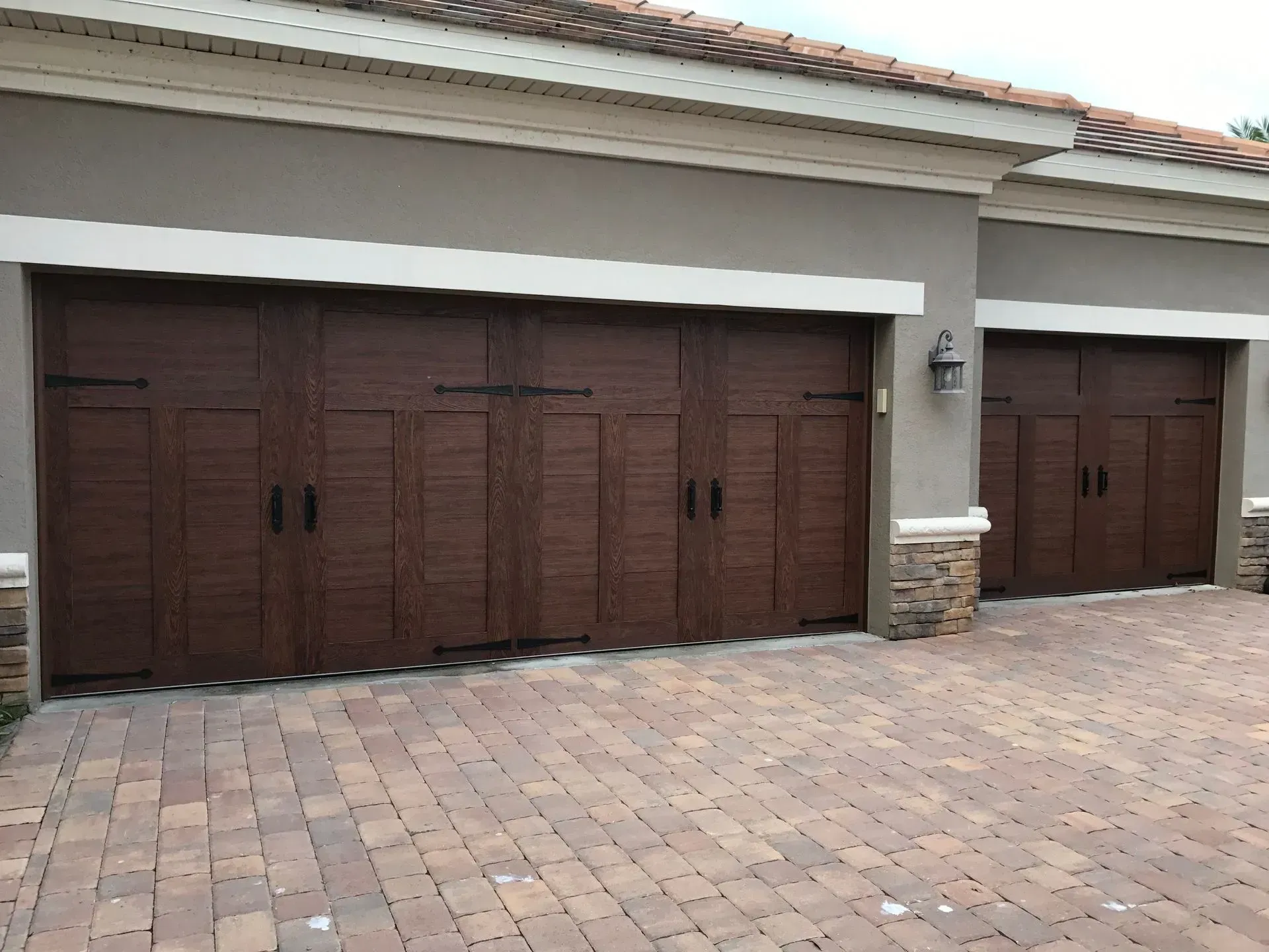 A house with a lot of garage doors and a brick driveway.