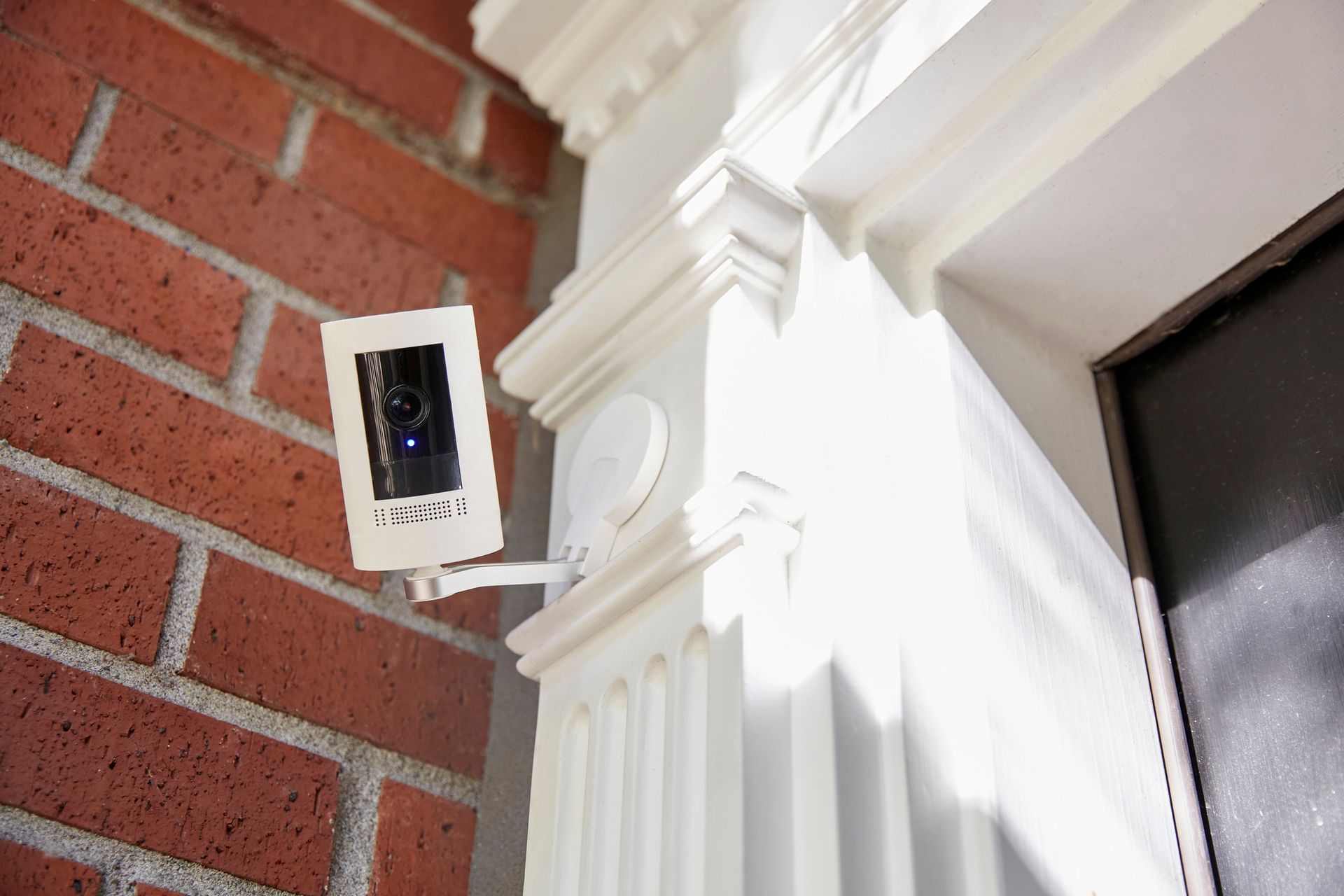 A security camera is mounted on the side of a brick building.