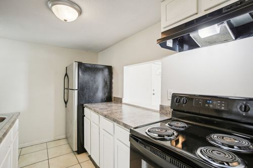 Kitchen with black appliances, white cabinets, and speckled countertops.