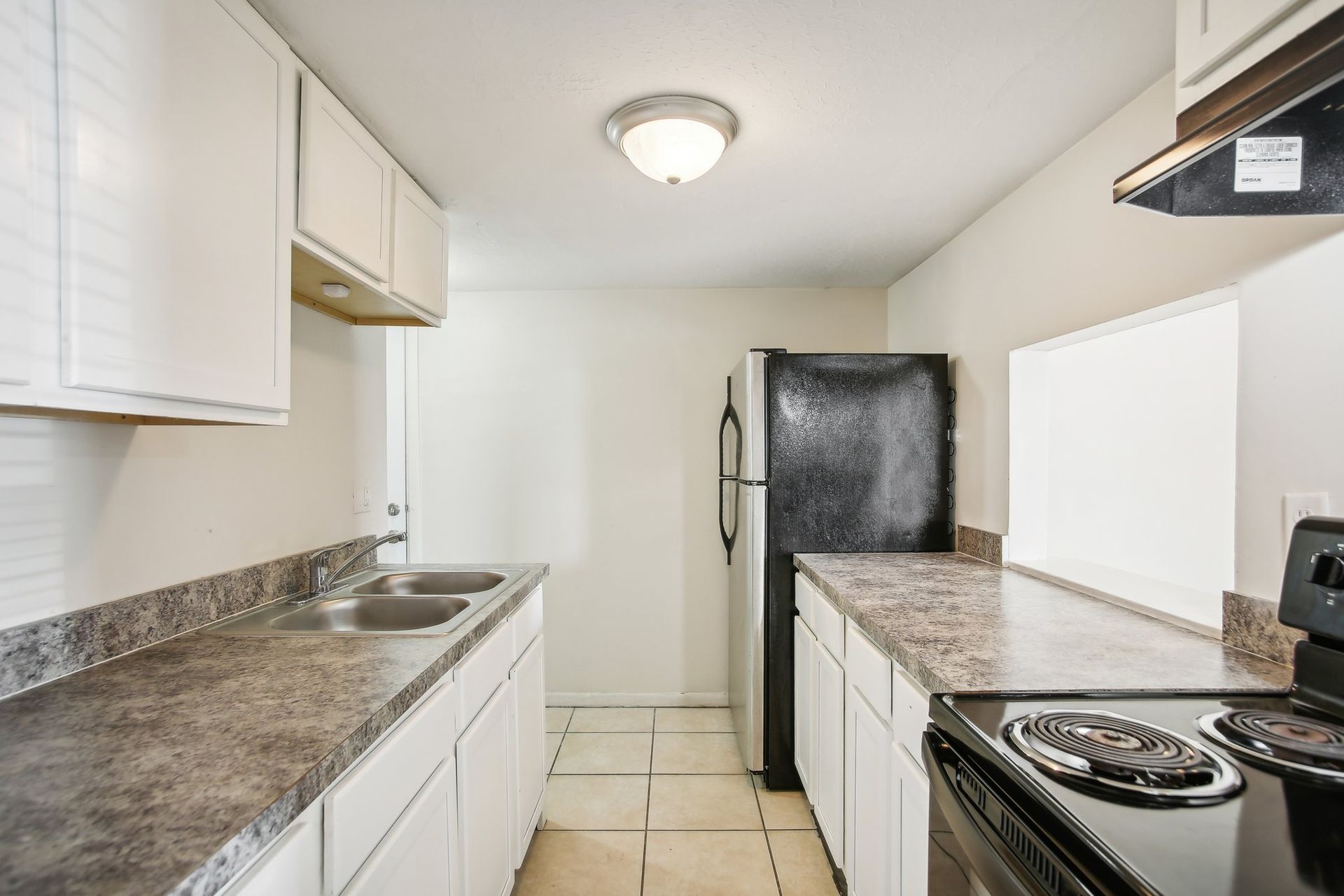Kitchen with white cabinets, dark countertops, black appliances, and a pass-through window.