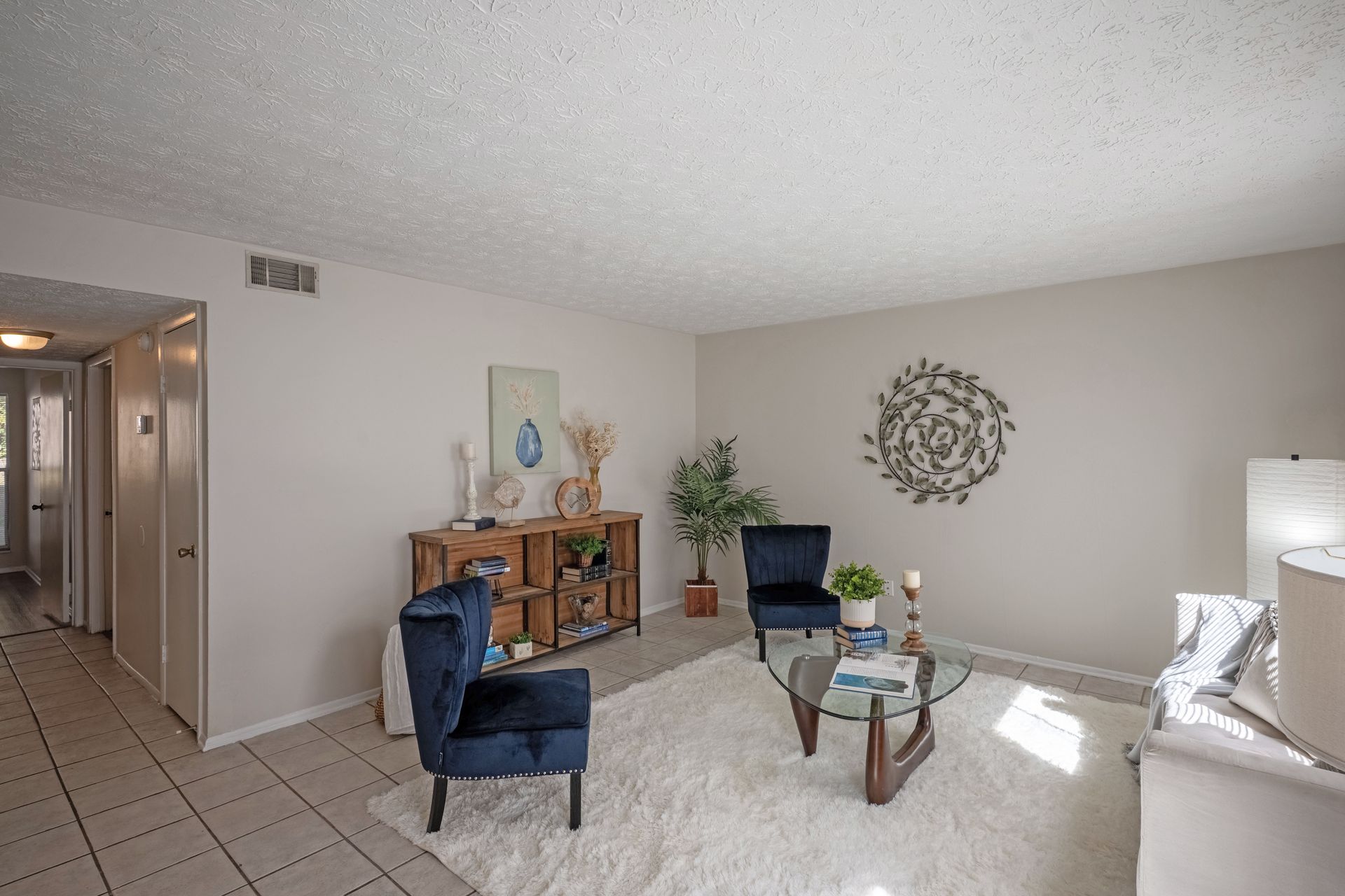 Living room with blue velvet chairs, rug, and wooden console table.