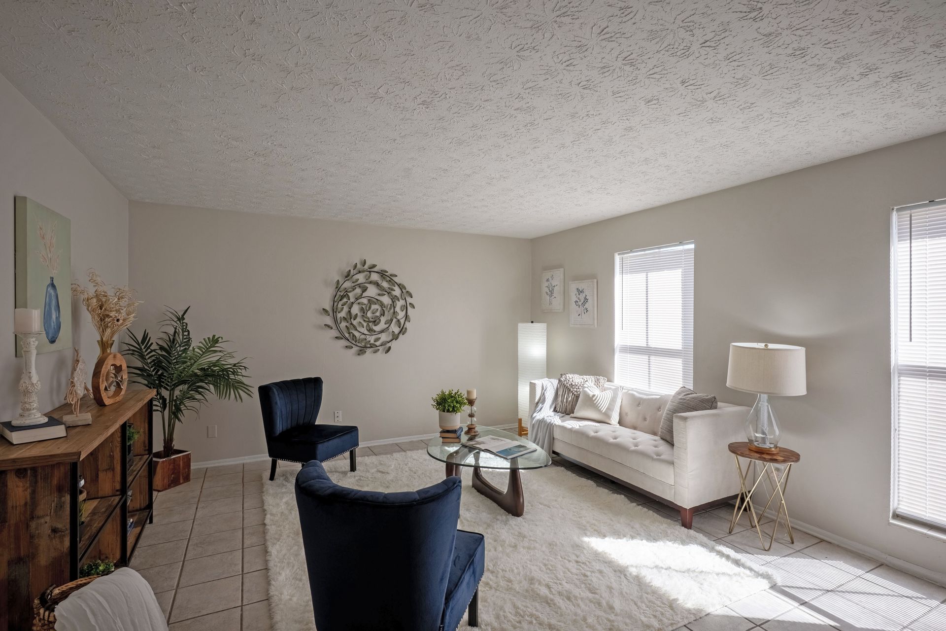 Living room with a white sofa, blue chairs, wooden furniture, and a rug.