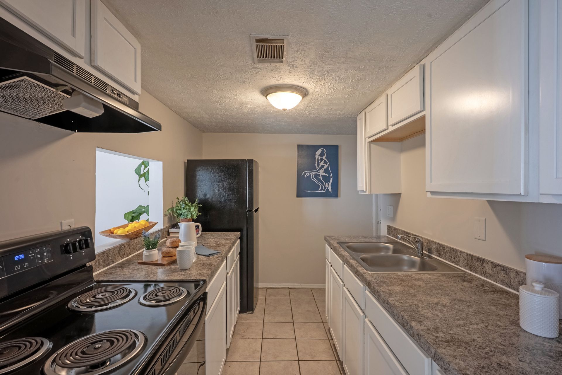 Kitchen with white cabinets, black appliances, and grey countertops.