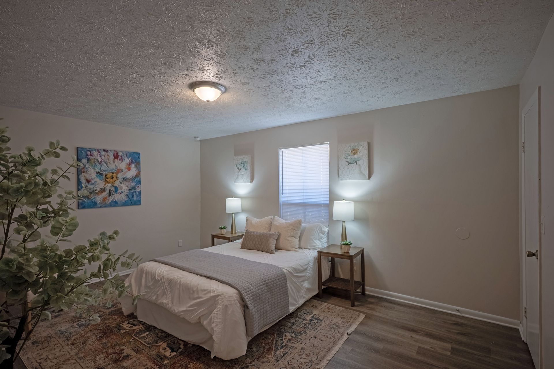 Bedroom with a bed, two nightstands, two lamps, artwork, and a window.