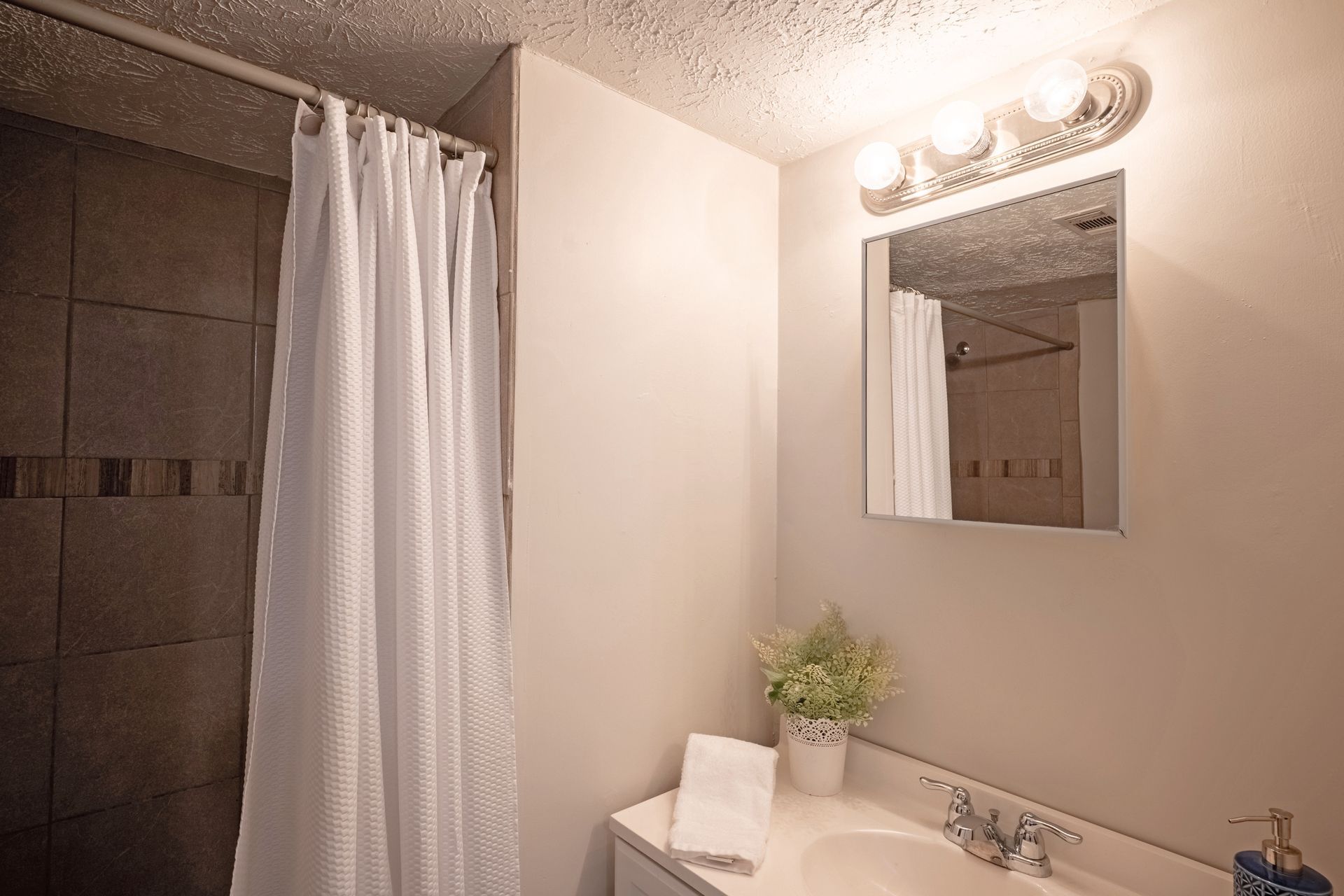 Bathroom with a shower, sink, mirror, and white shower curtain.