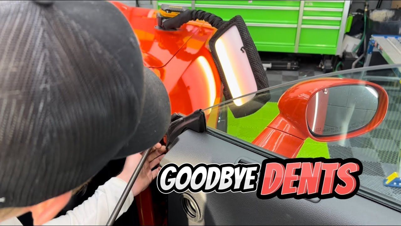 A person is working on a car with the words goodbye dents on the bottom