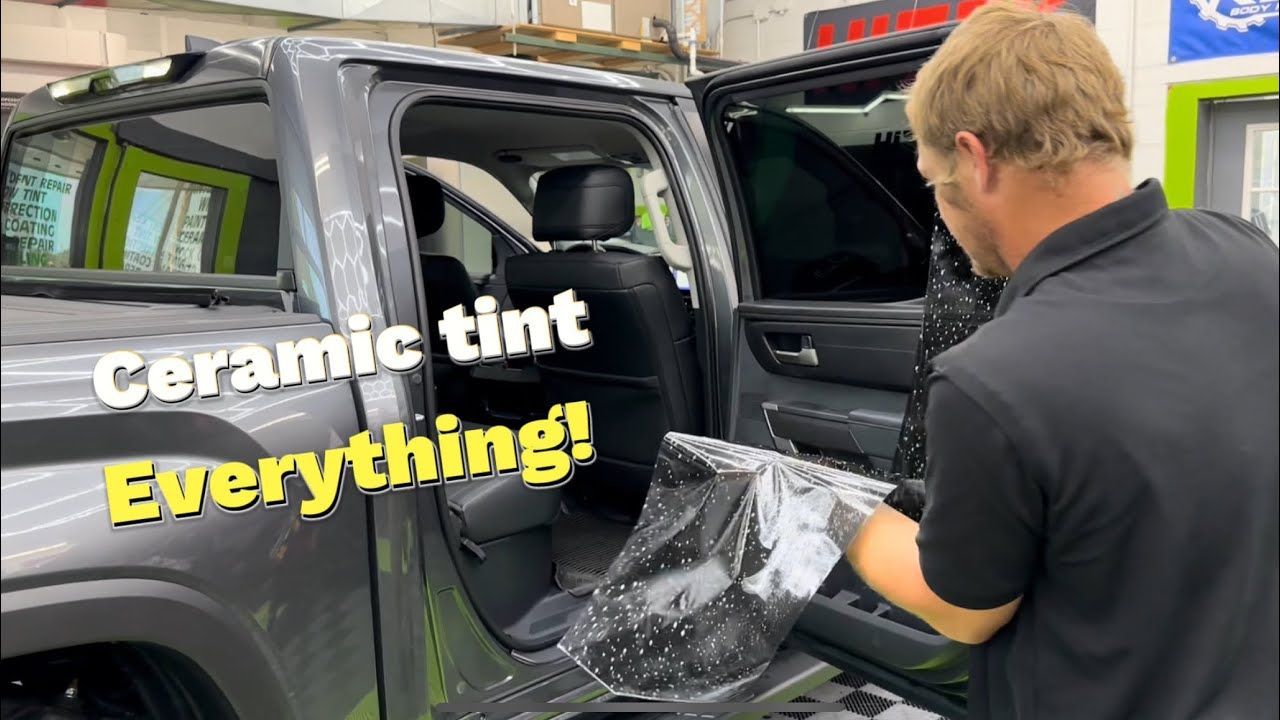 A man is applying ceramic tint to the windows of a truck.