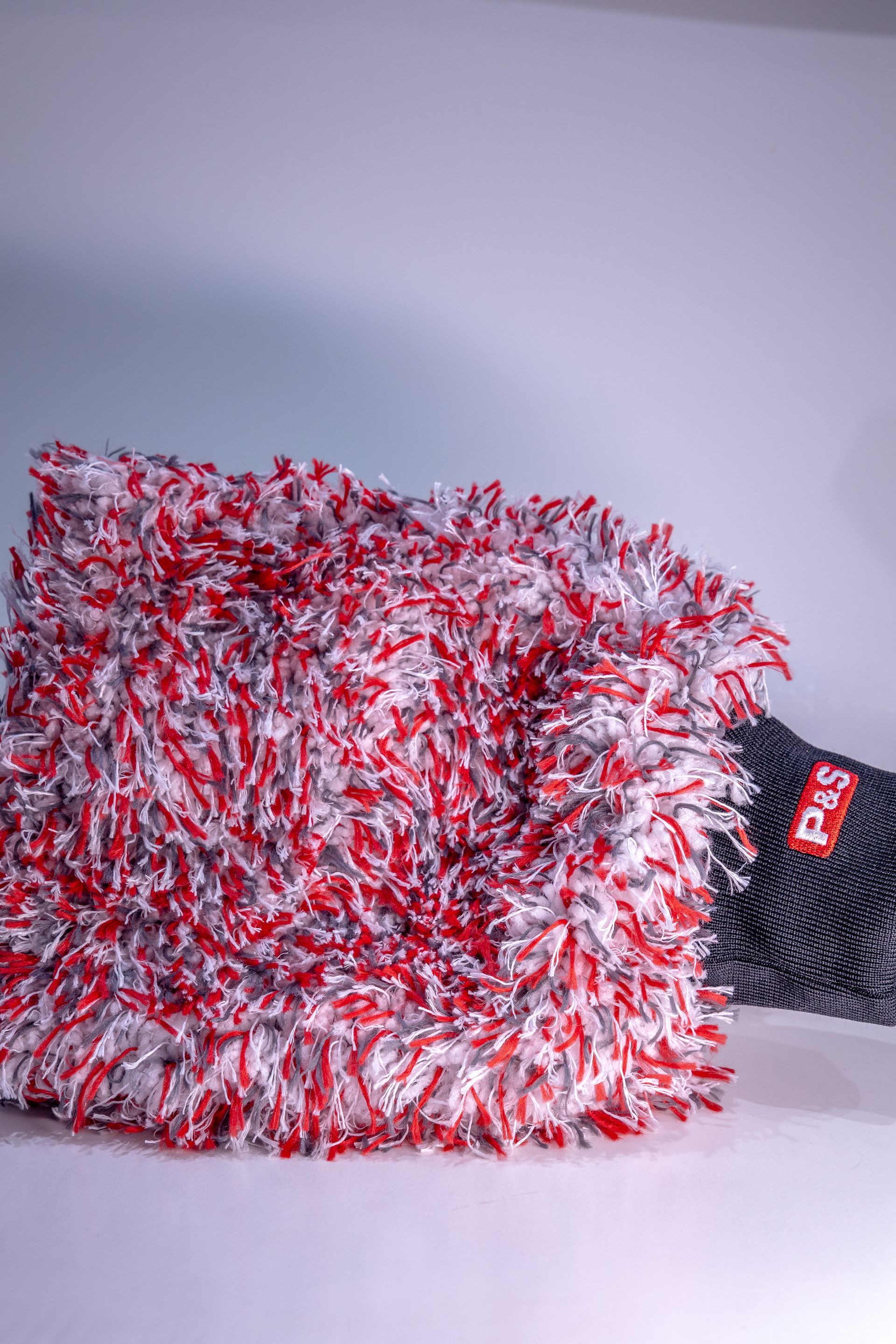 A red and white premium microfiber wash mitt is sitting on a white surface.