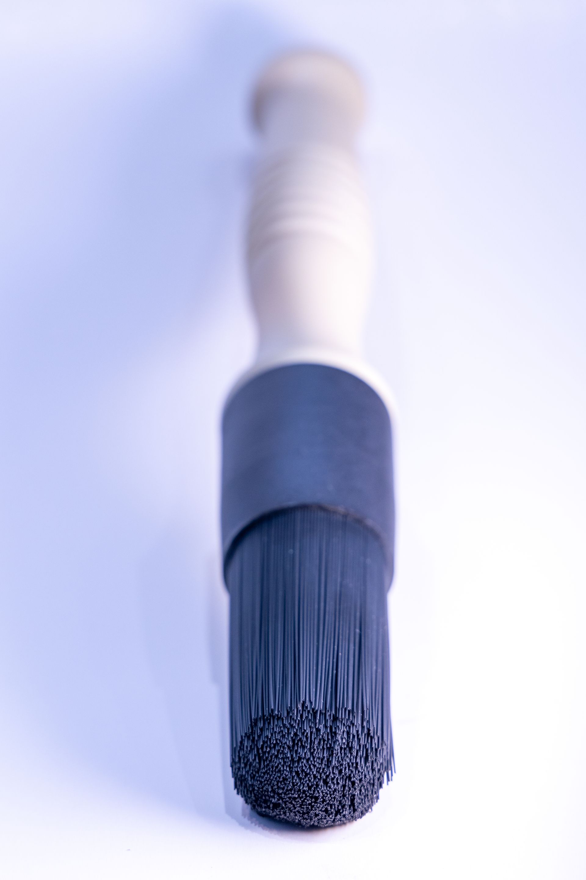 A black brush with a wooden handle on a white surface