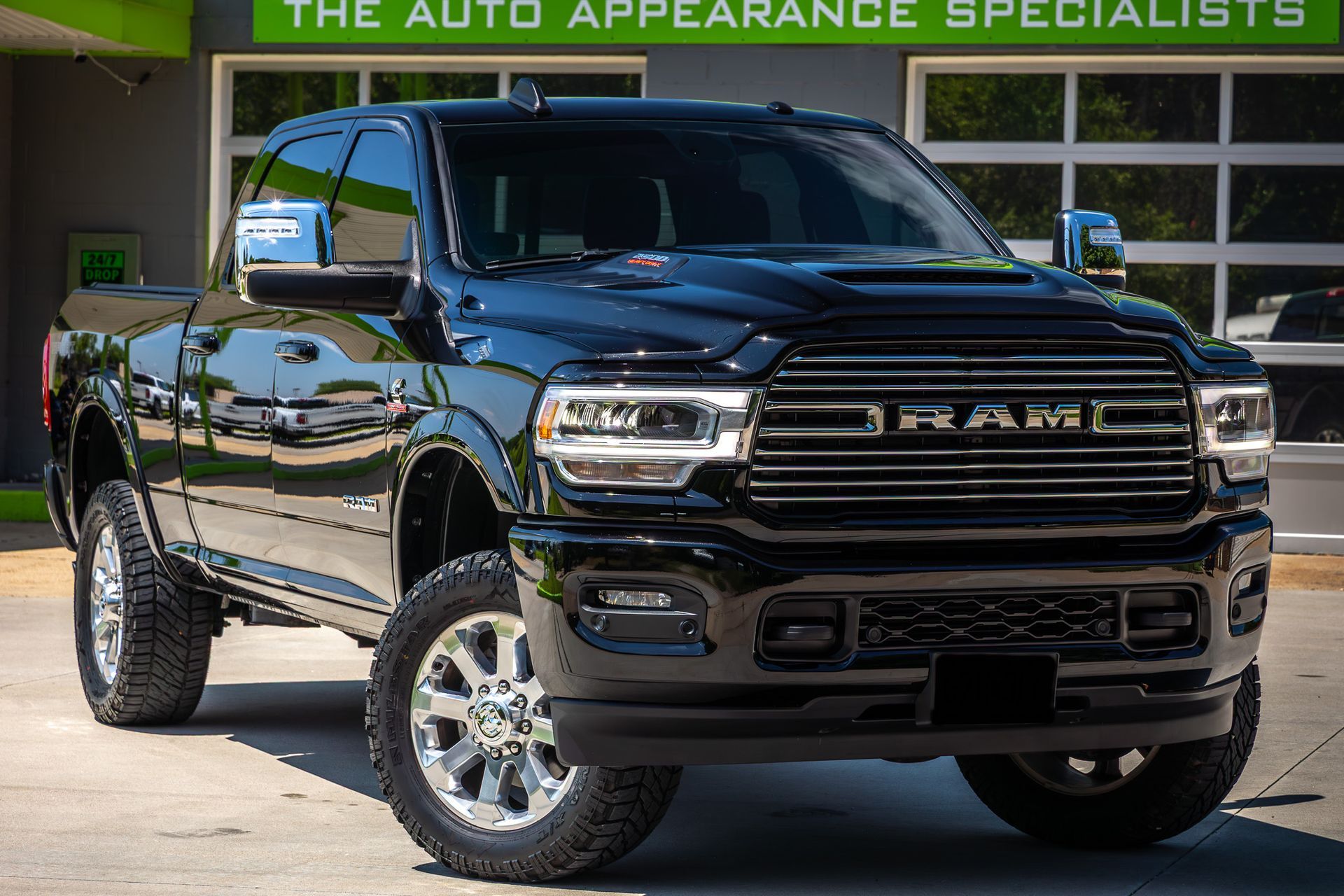 Black Ram pickup truck parked in front of a building with chrome wheels and a polished finish.