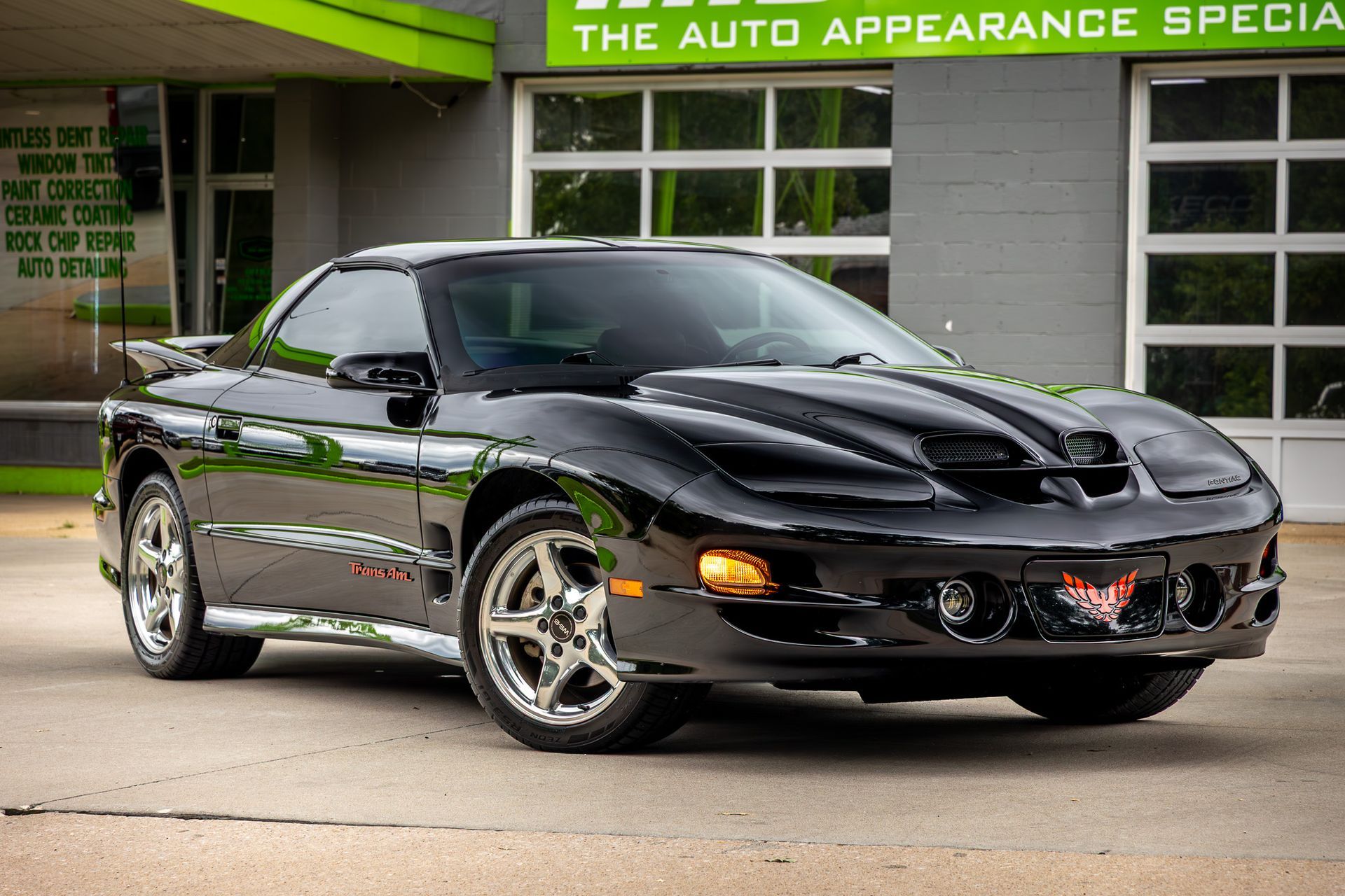 Black Pontiac Firebird Trans Am parked in front of a building.