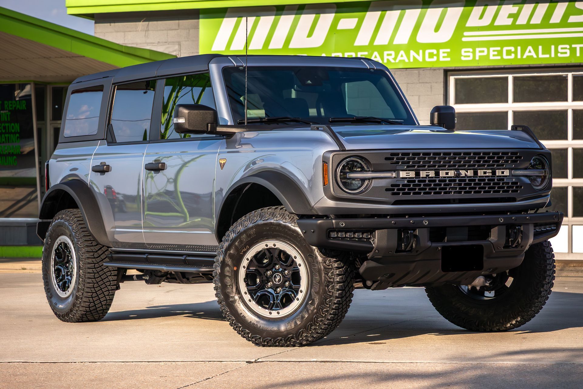 Silver Ford Bronco with black accents parked in front of a building.