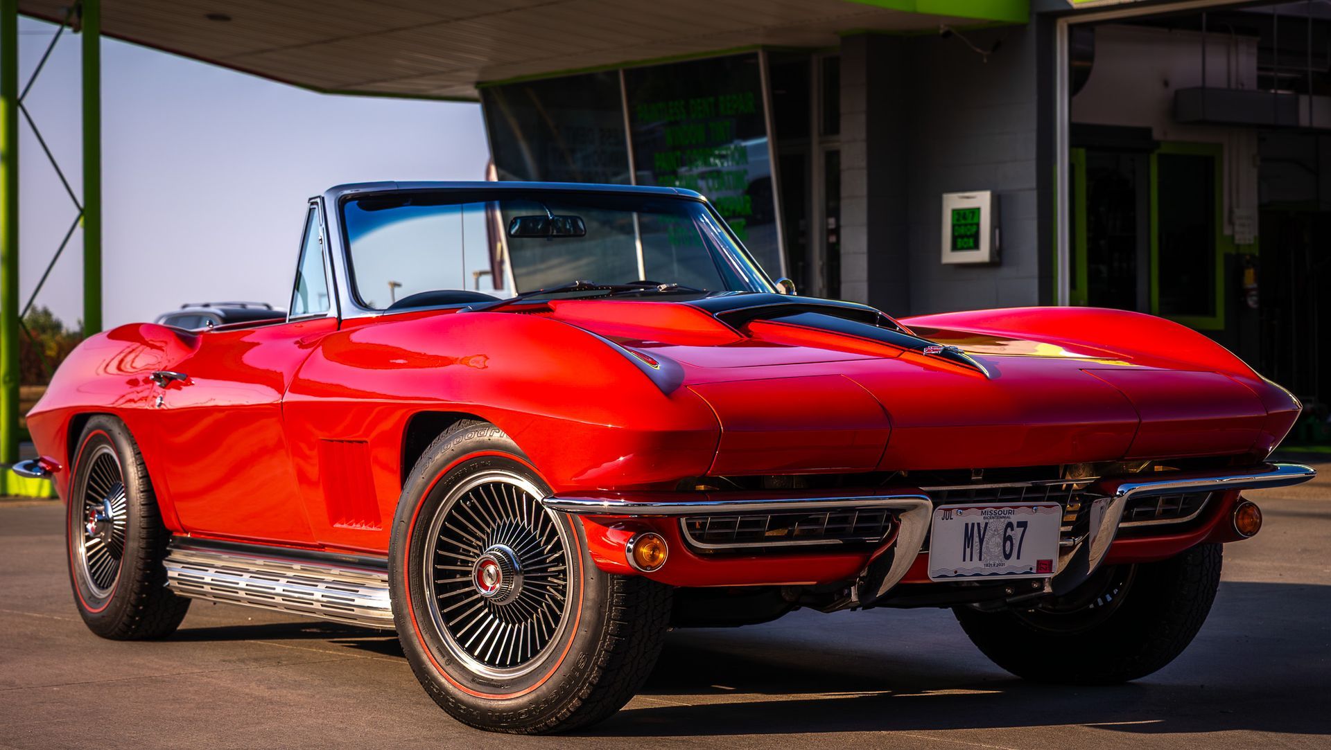 Red classic convertible car parked outdoors, black wheels, chrome accents.
